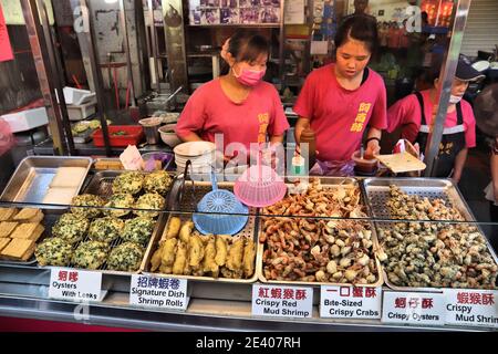 LUKANG, TAIWAN - 2. DEZEMBER 2018: Lebensmittelhändler verkaufen Austernkuchen, Garnelen und Krabben in Lukang Township in Taiwan. Lukang Stadt ist berühmt für sie Stockfoto