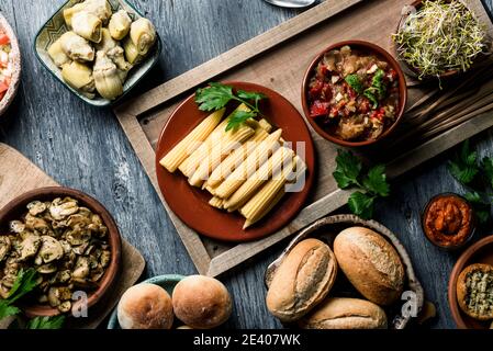 Blick aus der Perspektive auf einige verschiedene vegane Snacks, Beilagen, Dips, wie Guacamole oder Süßkartoffel Sobrasada, und einige andere Zutaten zuzubereiten Stockfoto