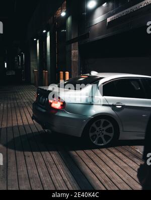 Vertikale Aufnahme eines silbernen Autos, das einen Parkplatz betritt Viel in der Nacht Stockfoto