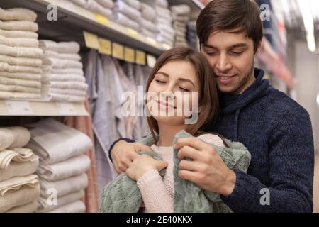 Glückliches Paar umarmt, versuchen warm kuschelig Kunstpelzdecke, während der Einkauf für Bettdecken in der Textilabteilung. Schöne Frau lächelt mit geschlossenen Augen, Stockfoto