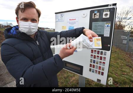 Gerolzhofen, Deutschland. Januar 2021. Menas Wolf, Geschäftsführer von Wolf Tabakwaren e.k., hält eine Maske mit Verpackung vor einem seiner Zigarettenautomaten. Der Tabakladen bietet die Schutzmasken in seinen Automaten an. Quelle: Karl-Josef Hildenbrand/dpa/Alamy Live News Stockfoto