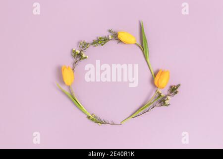 Kranz aus gelben Tulpenblüten auf violettem Hintergrund. Festlicher Rahmen mit Platz für Kopien. Stockfoto