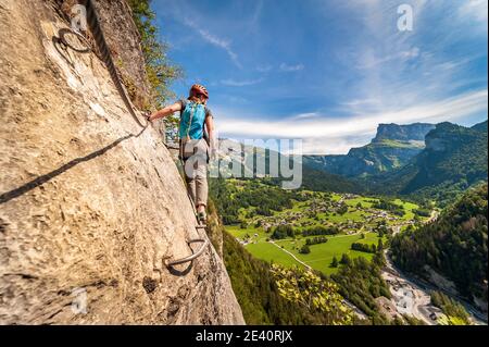 Klettersteig in Mont-Sixt-Fer-a-Cheval (Französische Alpen). Junge Frau auf Klettersteig-Route, eine Mischung aus Wandern und Bergsteigen durch kurze Seile unterstützt, c Stockfoto