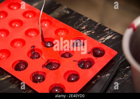 Die Füllung in einer Silikonform aufklappen. Der Prozess der Herstellung von Schokolade mit Füllung. Nahaufnahme. Stockfoto