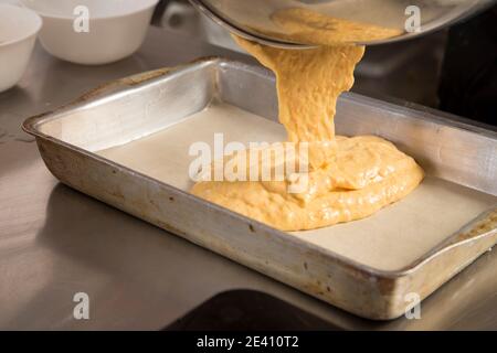 Den Teig in eine Backform aus Metall geben. Der Prozess der Herstellung von Cookies mit Karotten. Nahaufnahme. Stockfoto