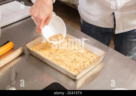 Ein Haufen Pinienkerne auf dem Teig in einer Auflaufform. Der Prozess der Herstellung von Cookies mit Karotten. Nahaufnahme. Stockfoto