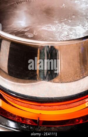Nahaufnahme der vertikalen Aufnahme eines Topfes kochendes Wasser auf einem Brenner auf hoch. Stockfoto