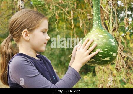 Kaukasische 8 Jahre alten Kind, Mädchen, glücklich, im Park, auf der Suche bei einer großen Flasche Kürbis Stockfoto