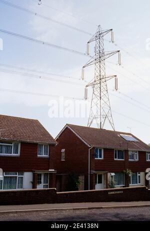 Strommasten, die aus dem fawley-Kraftwerk (Öl) kommen, sechziger Jahre Häuser in unmittelbarer Nähe, eines mit Sonnenkollektoren, fawley hampshire uk Stockfoto