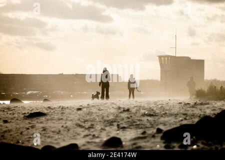 Kiel, Deutschland. Januar 2021, 21. Menschen, die am Strand bei stürmischem Wetter gegen das Licht laufen. Kredit: Frank Molter/Alamy Live Nachrichten Stockfoto