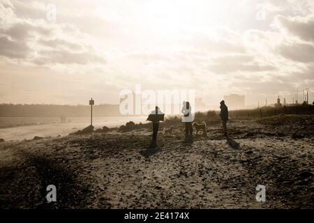 Kiel, Deutschland. Januar 2021, 21. Menschen, die am Strand bei stürmischem Wetter gegen das Licht laufen. Kredit: Frank Molter/Alamy Live Nachrichten Stockfoto