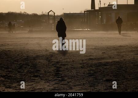 Kiel, Deutschland. Januar 2021, 21. Menschen, die am Strand bei stürmischem Wetter gegen das Licht laufen. Kredit: Frank Molter/Alamy Live Nachrichten Stockfoto