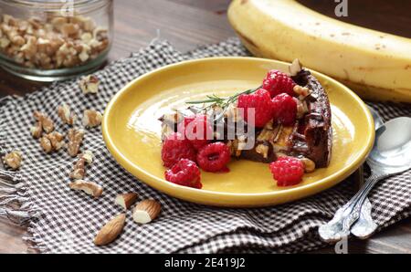 Schokolade vegane Brownie Kuchen mit Banane dekoriert mit Himbeere, Walnuss und Rosmarin, Nahaufnahme, Kopierraum, vegane eggfree Desserts Konzept Stockfoto