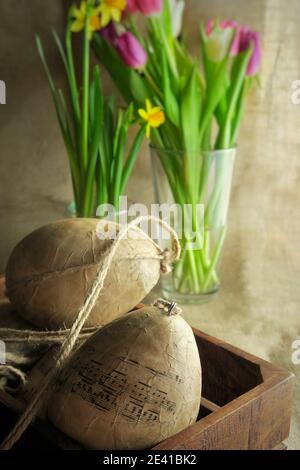 Ostereier mit Decoupage Technik in Holz verziert. VAE von bunten Tulpen und Narzissen auf dem Hintergrund. DIY-Konzept. Stockfoto