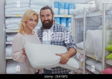 Haus, Immobilienkonzept. Reifes Paar, das im Kaufhaus Bettwäsche und Kissen kaufen kann, Kopierplatz. Fröhlicher Mann und Frau kaufen Ort Stockfoto