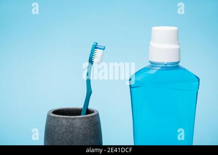 Zahnbürste und Flasche Mundwasser auf blauem Hintergrund Stockfoto