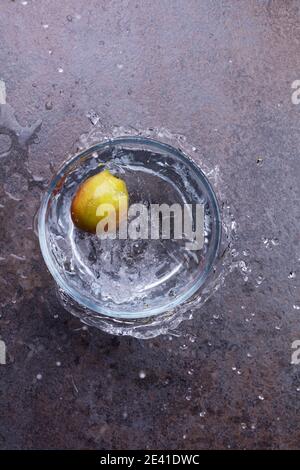 Hi-Speed Schuss eines Apfels, der in eine Glasschale voller Wasser fällt. Aufnahme in 1/2000 Sekunde. Stockfoto