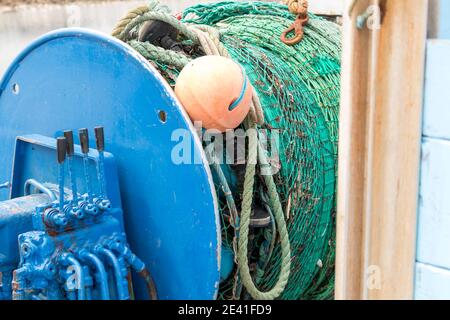 Aufgerollte industrielle Fischernetze auf einer Winde an Bord einer Blaufischboot oder Trawler Stockfoto