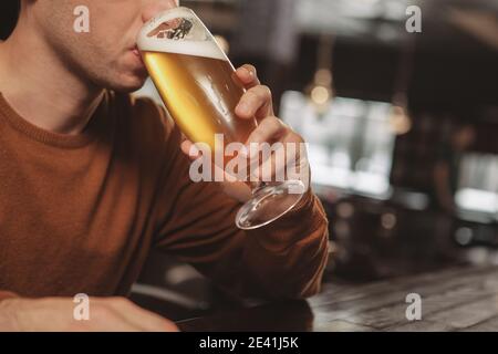 Nahaufnahme eines Mannes, der im Pub leckeres, frisch gebrautes Bier trinkt. Mann schlürft leckeres kühles Craft-Bier an der Bar, Copy Space. Das Ist Stockfoto