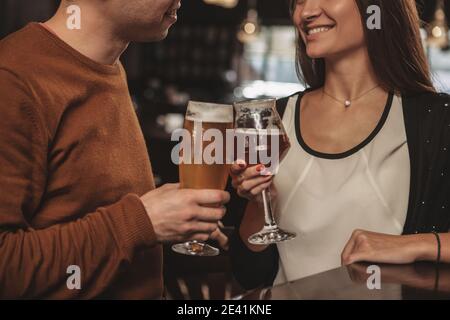 Selektiver Fokus auf Gläser Bier, die in den Händen des Paares zum Jubiläum im Restaurant klirren. Kurzer Schuss eines liebevollen Paares toasten Witz Stockfoto