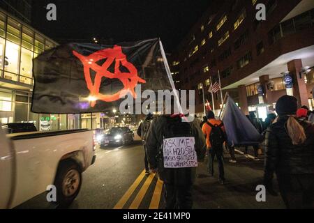 20. Januar 2021, Boston, Massachusetts, USA: Anti-Trump-Protestler mit einer Anarchie-Flagge, die ein Care Pack bei einem marsch durch die Innenstadt von Boston trägt, nach der Kundgebung "Keine Flitterwochen für Biden", die eine progressive Agenda für eine neu gewählte Biden-Harris-Regierung auf Boston Common fordert. Quelle: Keiko Hiromi/AFLO/Alamy Live News Stockfoto