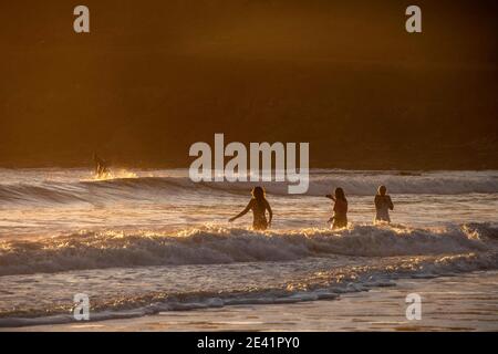 Swansea, Großbritannien. Januar 2021. Schwimmer und Surfer genießen das goldene Licht, wenn die Sonne an diesem Nachmittag in der Langland Bay in der Nähe von Swansea untergeht. PIC von Lisa Dawson Rees Kredit: Phil Rees/Alamy Live Nachrichten Stockfoto