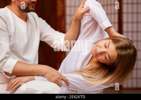 Junge Frau streckt ihren Körper mit Hilfe von professionellen thai Massage Therapeut im Spa-Center. Männlich Masseur Durchführung thai massage auf seine Client Stockfoto