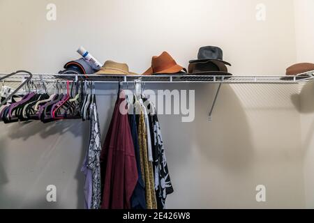 Ein meist leerer Gang in einen chaotischen Schrank mit einigen hängen Kleidung und Hüte Stockfoto