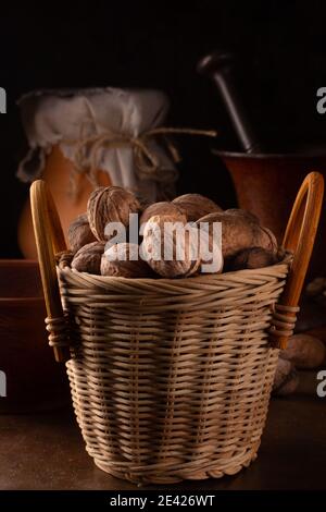 Ganze Walnüsse in einem Weidenkorb auf dunklem Hintergrund Stockfoto