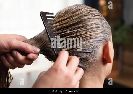 Friseur tun Behandlung nach der Anwendung Haarfärbung, Haarfärbemittel für eine blonde Frauen zu Hause oder im Salon. Stockfoto