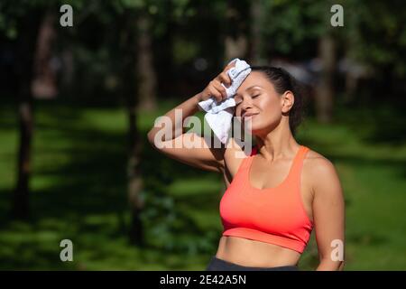Müde sportliche Frau wischen ihr Gesicht mit Handtuch nach produktiven Ausübung im Freien. Stockfoto