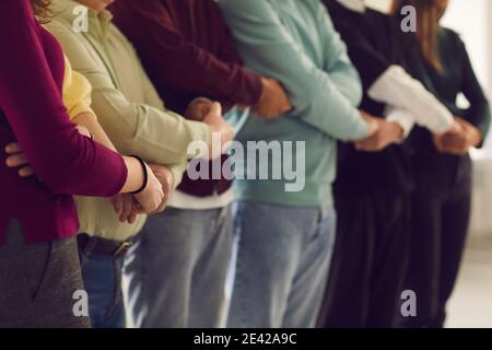 Gruppe von Menschen, die zusammen stehen und die Hände halten, sich gegenseitig unterstützen und ihre Einheit zeigen Stockfoto