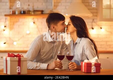 Junge liebevolle Paar Mann und Frau sitzen küssen einander Während Valentinstag Feier Stockfoto