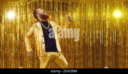 Lustiger ungehemmter Mann in einem glänzenden goldenen Anzug, der Lieder singt Und Spaß auf einer Party Stockfoto
