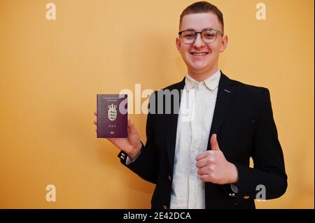 Junger hübscher Mann mit grönländischem Pass-ausweis auf gelbem Hintergrund, glücklich und zeigt Daumen hoch. Reise nach Europa Country Konzept. Stockfoto