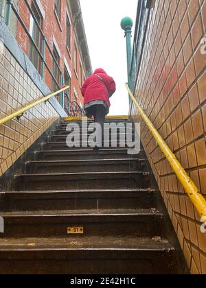 Frau steigt die steile Treppe aus der U-Bahn an der 15th Street auf der Linie F in Brooklyn, New York. Stockfoto