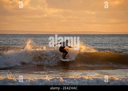 Swansea, Großbritannien. Januar 2021. Surfer reiten die Wellen, wenn die Sonne untergeht in Langland Bay in der Nähe von Swansea an diesem Nachmittag. PIC von Lisa Dawson Rees Kredit: Phil Rees/Alamy Live Nachrichten Stockfoto