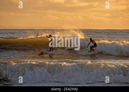 Swansea, Großbritannien. Januar 2021. Surfer reiten die Wellen, wenn die Sonne untergeht in Langland Bay in der Nähe von Swansea an diesem Nachmittag. PIC von Lisa Dawson Rees Kredit: Phil Rees/Alamy Live Nachrichten Stockfoto