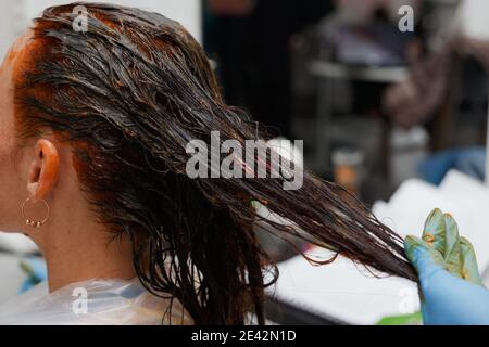 Friseursalon. Haarfärbung im Prozess. Frau färbt Haare in dunkler Farbe. Stockfoto