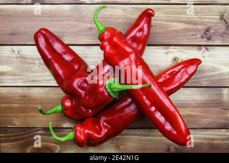 Nahaufnahme der isolierten Gruppe 4 rot reifen rohen spitzen Paprika Haufen, Holz Holzplanken Hintergrund Stockfoto