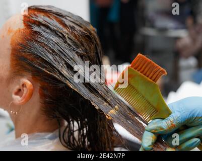 Friseursalon. Haarfärbung im Prozess. Frau färbt Haare in dunkler Farbe. Stockfoto