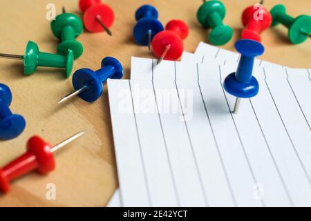 Büroklammern aus Metall und bunte Stecknadeln mit einigen Blättern Auf einem Holztisch Stockfoto