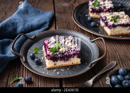 Köstliche saftige Dessert, Heidelbeer Pie Scheiben gekrönt mit einem süßen knusprigen Streusel, mit frischen Beeren auf rustikalem Holzhintergrund dekoriert Stockfoto
