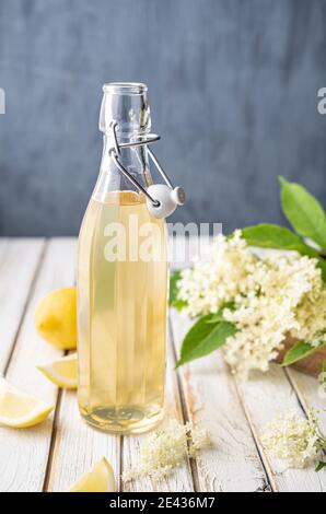 Köstliches gesundes Erfrischungsgetränk, süßer Holunderblütensirup oder Cordial in einer Glasflasche auf rustikalem Holzhintergrund Stockfoto