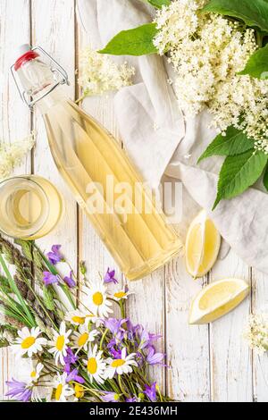 Köstliches gesundes Erfrischungsgetränk, süßer Holunderblütensirup oder Cordial in einer Glasflasche auf rustikalem Holzhintergrund Stockfoto