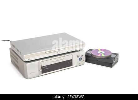 DVD-Player über vhs-Player neben Videobändern und cds isoliert auf weißem Hintergrund. Stockfoto