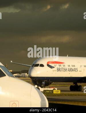 London, England - Januar 2018: British Airways Boeing 787 „Dreamliner“ hinter der Nase eines kleinen Passagierjets Stockfoto