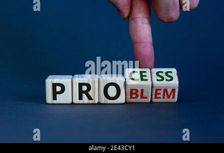 Problem- oder Prozesssymbol. Geschäftsmann Hand dreht Holzwürfel und ändert das Wort "Problem" zu "Prozess". Schöner grauer Hintergrund. Business und PR Stockfoto