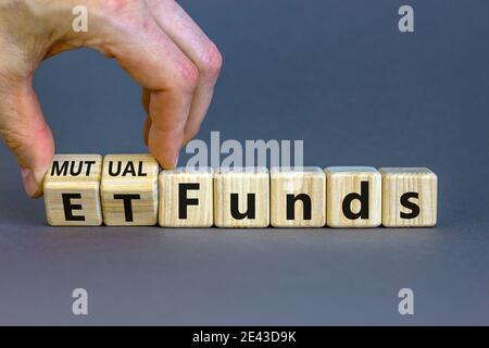 Investmentfonds vs. ETF-Symbol. Geschäftsmann dreht einen Würfel und ändert Wörter 'ETF, Exchange-Traded Fund' in 'Utual Funds. Schöner grauer Hintergrund, Kopie s Stockfoto