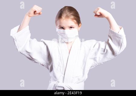 Mädchen in einem Kimono Judo. Zeigt Stärke. Isoliert auf grauem Hintergrund. Hochwertige Fotos Stockfoto